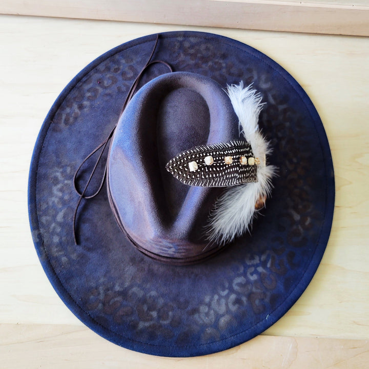 Navy blue leopard-print cowgirl hat with feather-and-bead accent hatband