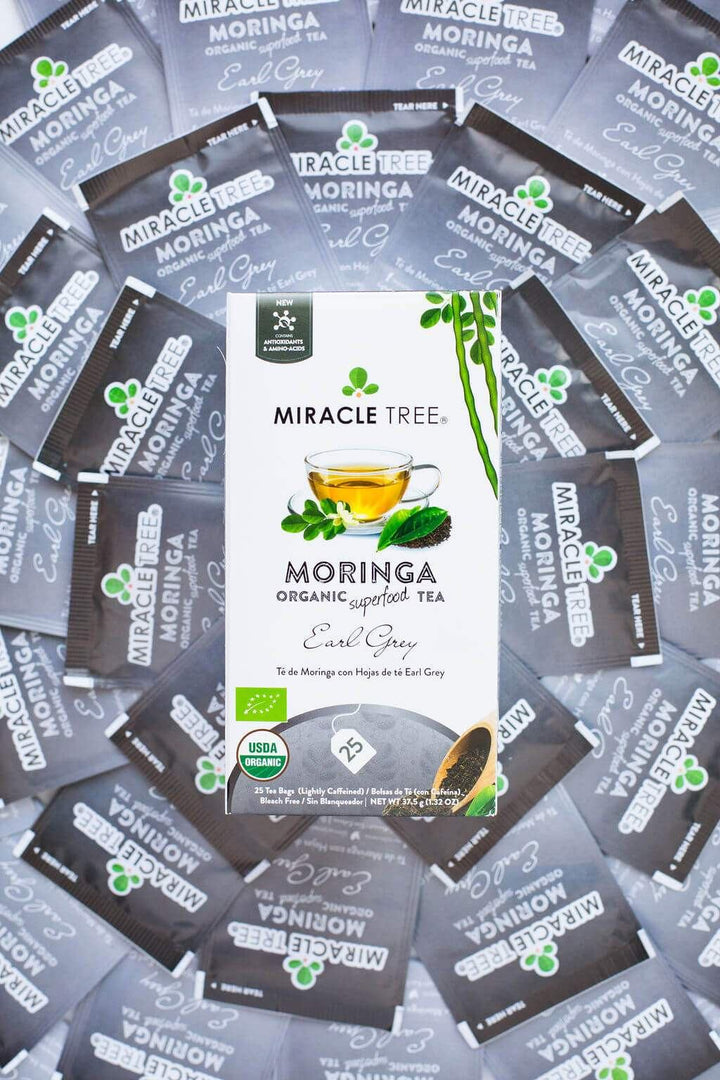 Assorted organic moringa Earl Grey tea box packs scattered with green leaf and badge icons
