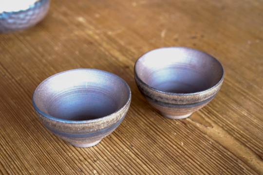 Two ceramic sauce dipping bowls, brown-bronze exterior and dark interior surfaces