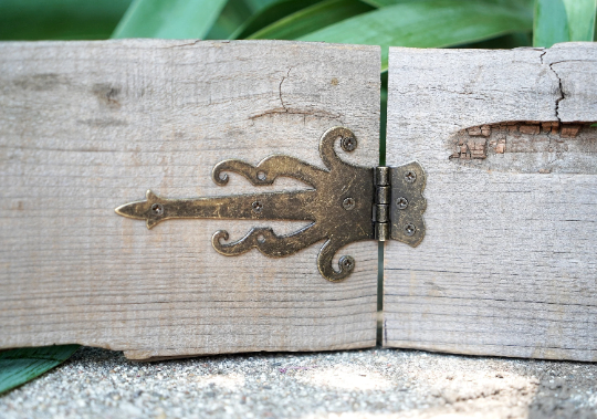 Bronze decorative strap hinge mounted on a wooden door seam
