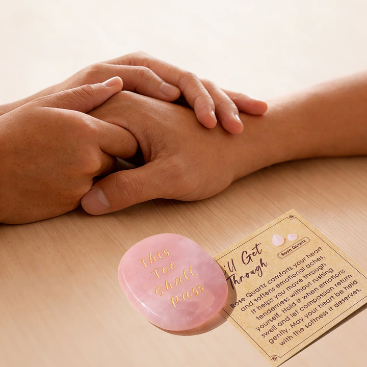 Pink heart-shaped crystal stone with gold lettering, beside instruction card