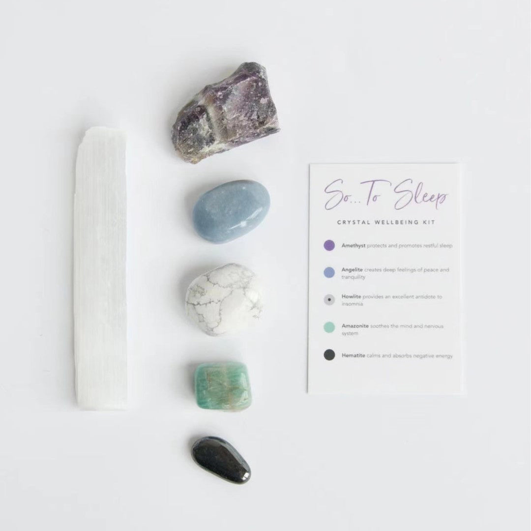 Crystal healing kit with white selenite wand, purple, blue, and green stones, and card.