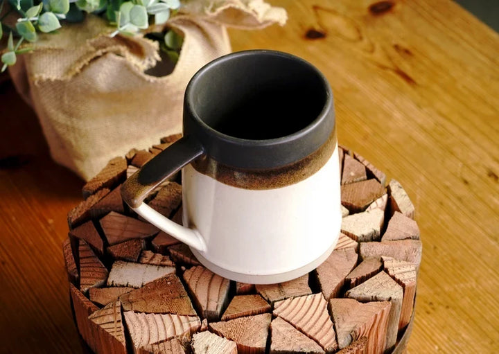 Ceramic mug with black interior, dark brown speckled rim, white exterior and handle