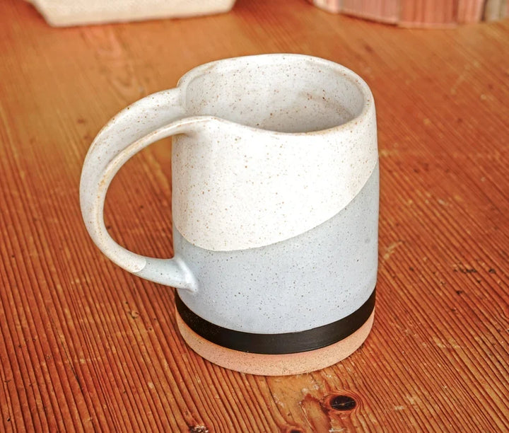 Speckled ceramic mug with side handle and dark band near the bottom