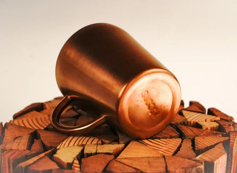 Copper double wall stainless steel mug lying on chopped wood