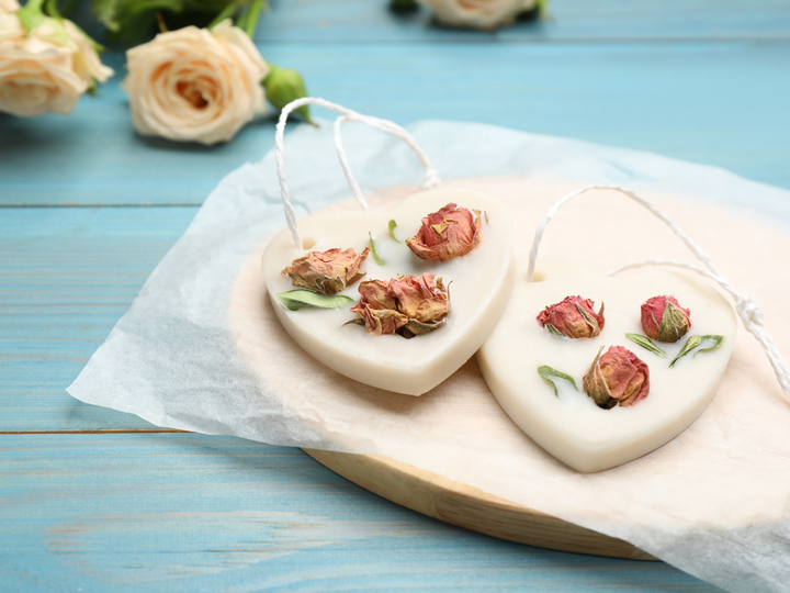Heart-shaped wax sachets with dried rose petals and herbs, on parchment