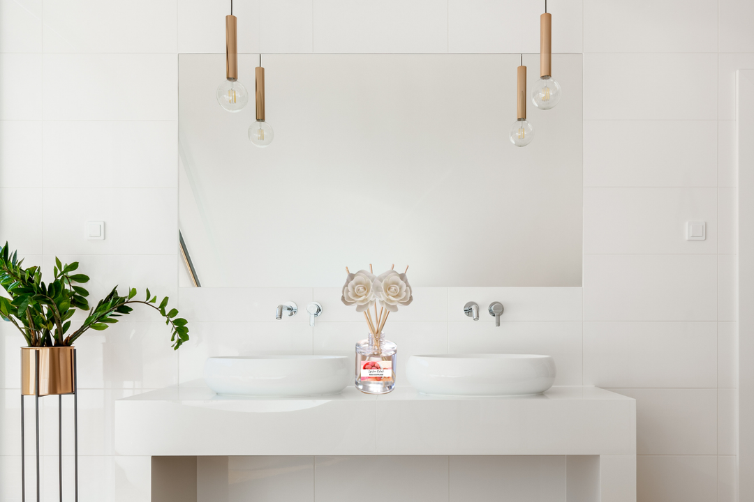 Reed diffuser bottle with wooden reeds on white bathroom sink counter