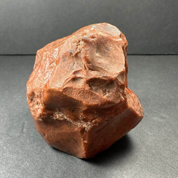Raw reddish-brown obsidian stone with uneven surface texture and rounded irregular shape