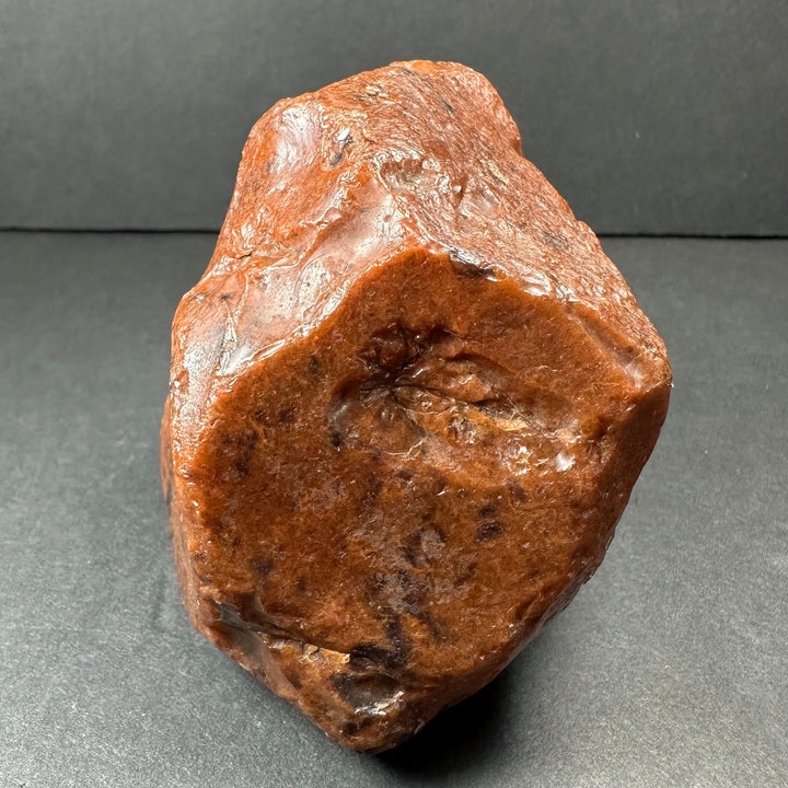 Raw reddish-brown obsidian stone with rough, glassy texture and irregular shape