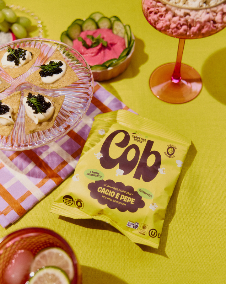 Seriously Cheesy corn-free popcorn snack bag on a green table with desserts