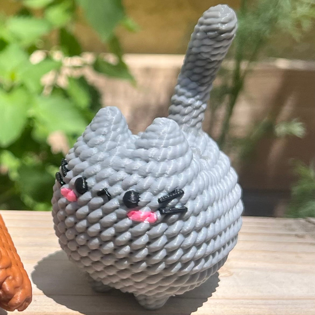 Knitted gray cat plush with raised handle, pink nose and whiskered face detail