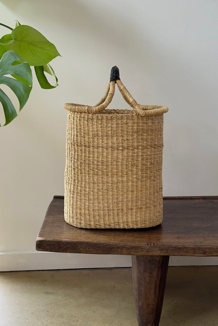 Woven round pot basket with top handle and dark fabric loops, natural tan weave