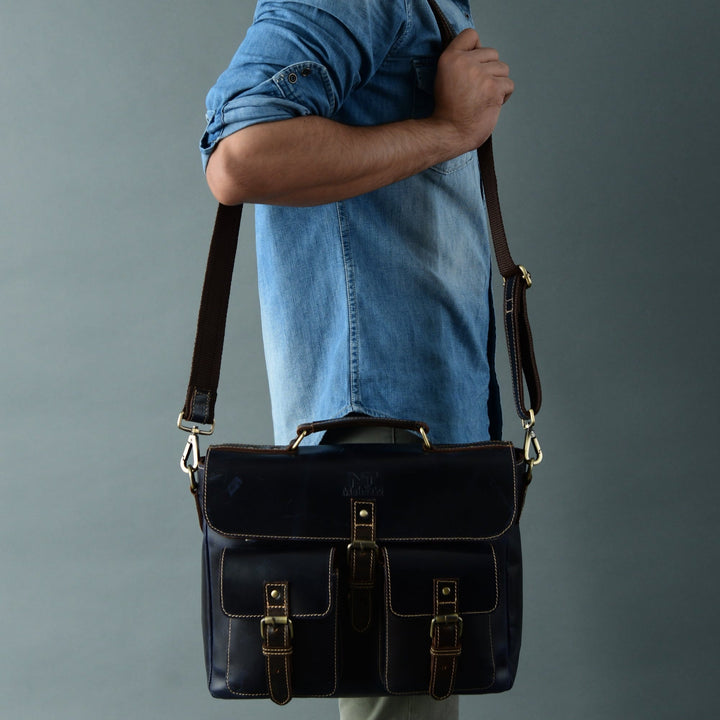Dark blue laptop messenger bag on model with side buckled flap and shoulder strap