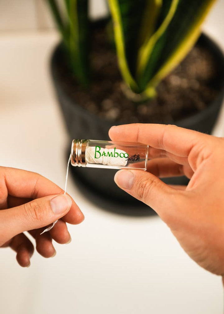 Bamboo floss in a small glass vial, held by hands