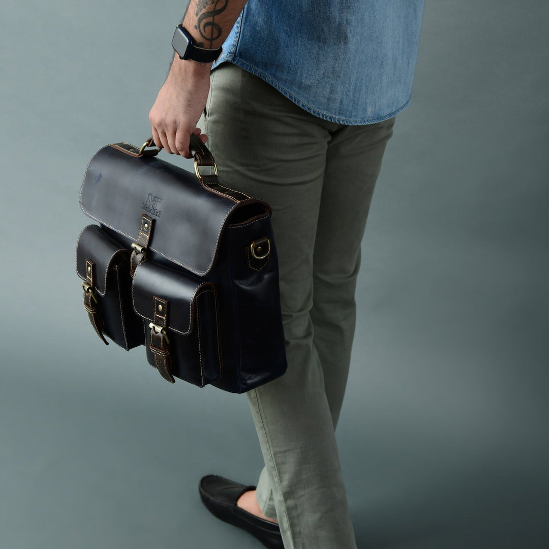 Dark blue laptop messenger bag on model, side profile with front buckle accents