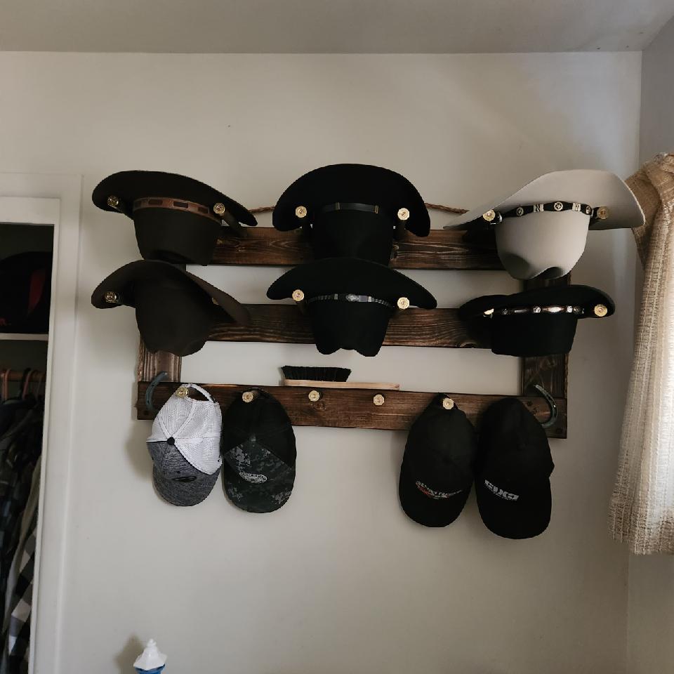 Horizontal wall-hanging hat organizer with black and light hats on three wooden bars