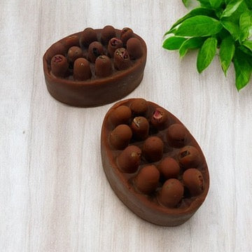 Brown massage bar soap with rounded nodules in oval soap dishes
