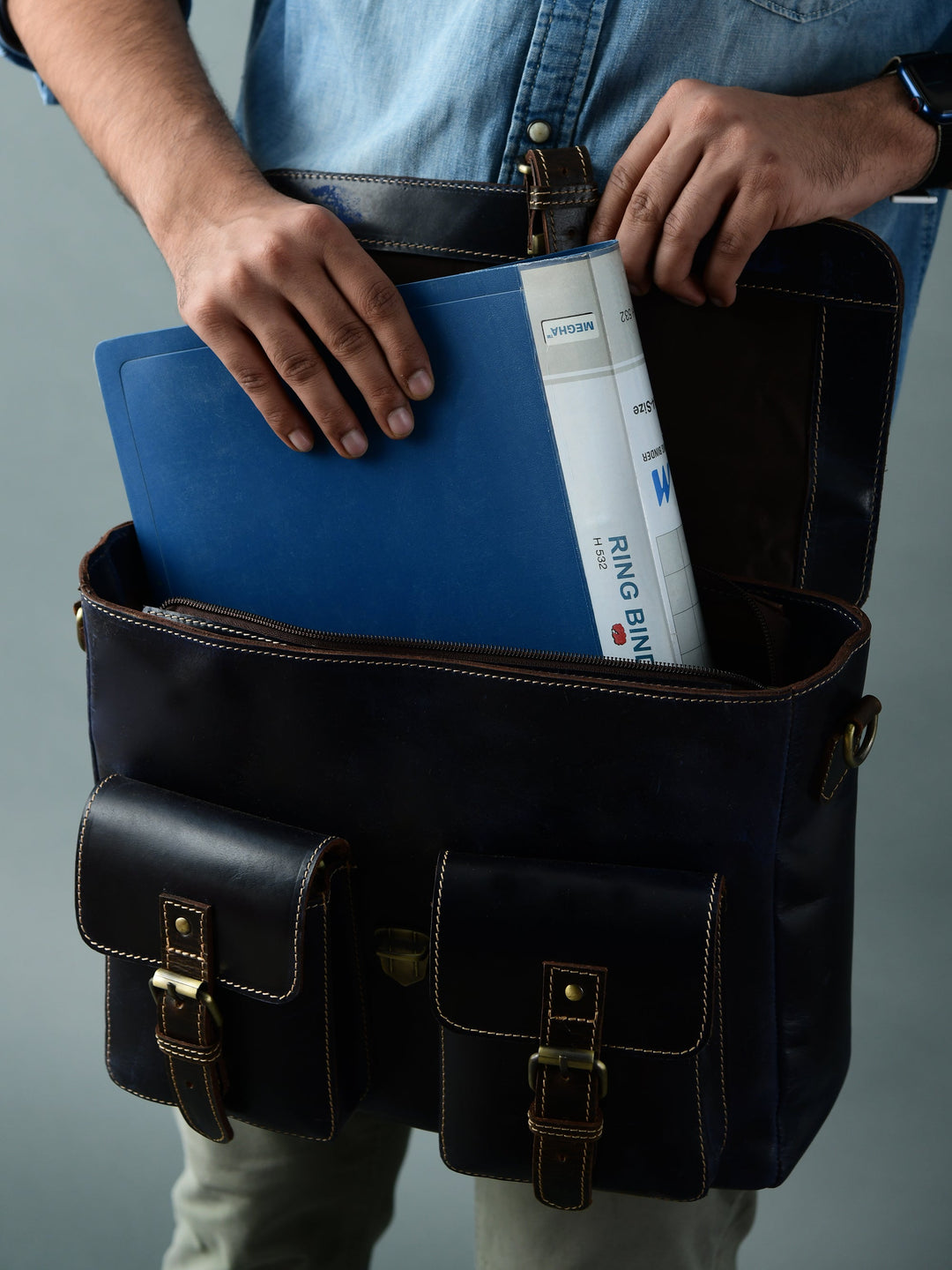 Dark blue leather laptop messenger bag with front buckle pockets, open top showing laptop