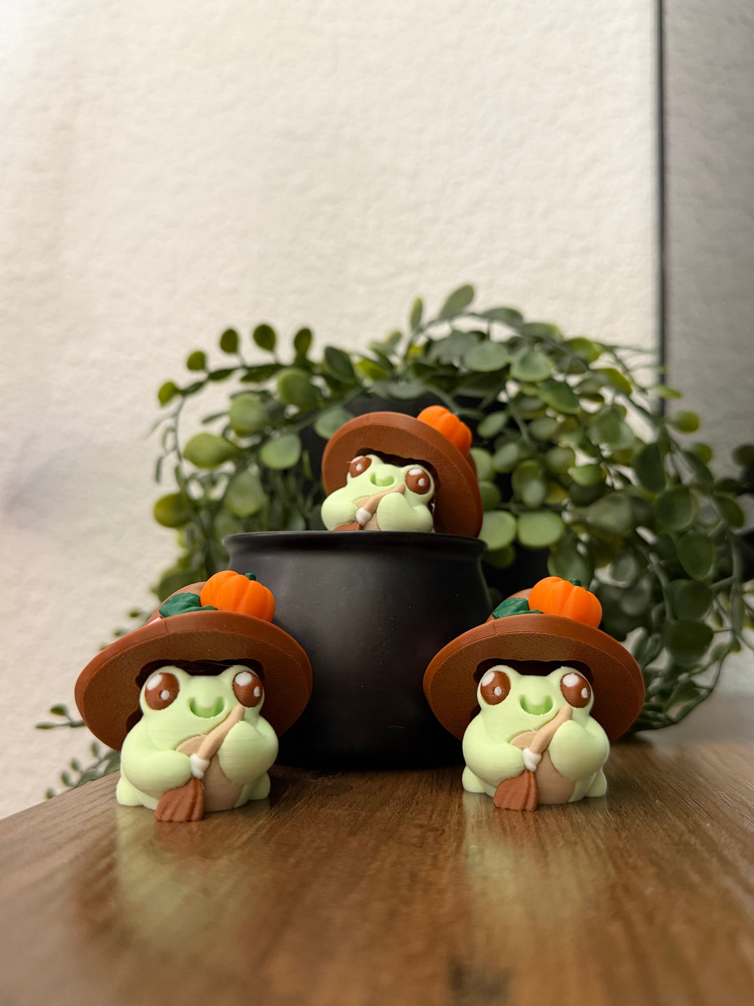 Frog toy group with orange witch hats, sitting inside a black cauldron