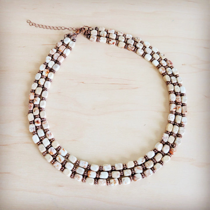 Layered triple-strand beaded necklace with white, bronze and black cube beads