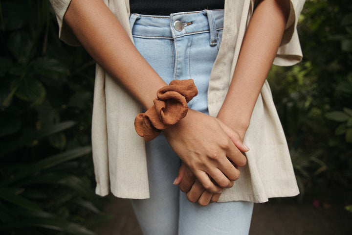 Rust scrunchie on the wrist, gathered fabric scrunch with elastic band.