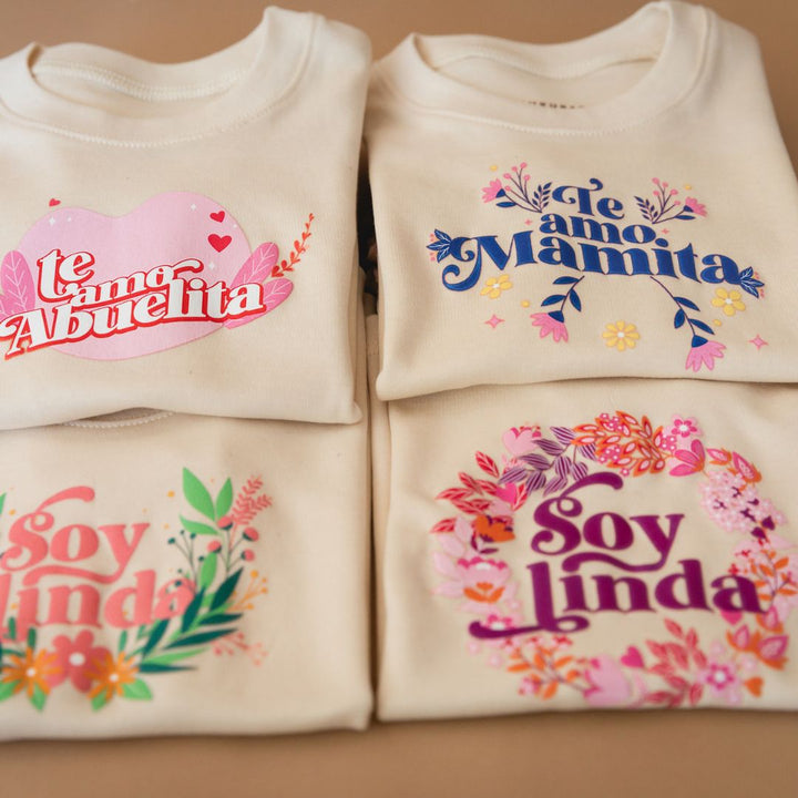 Cream graphic tee designs: "Te amo Abuelita", "Te amo Mamita", "Soy linda"