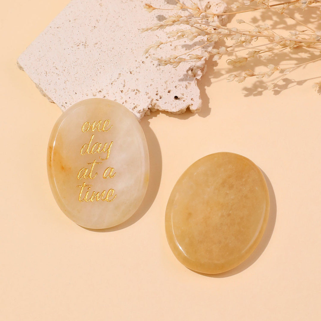 Light beige round pocket crystal stone with gold “one day at a time” text