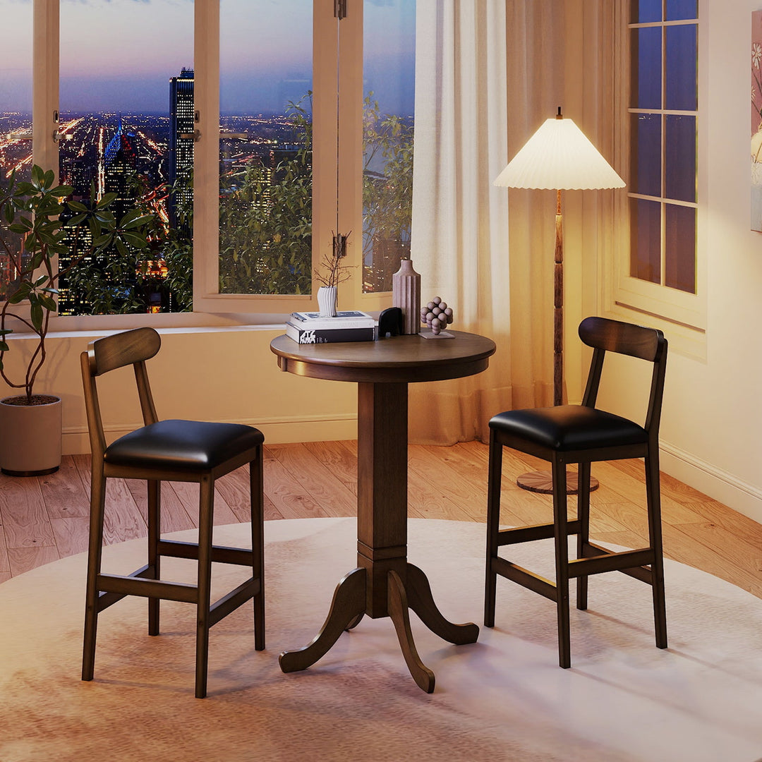 Round pub table and two armless stools with dark wood frames and black padded seats