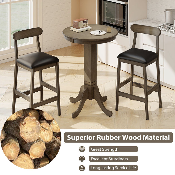 Round pub table and two stools near fireplace; dark wood frames and black seat cushions