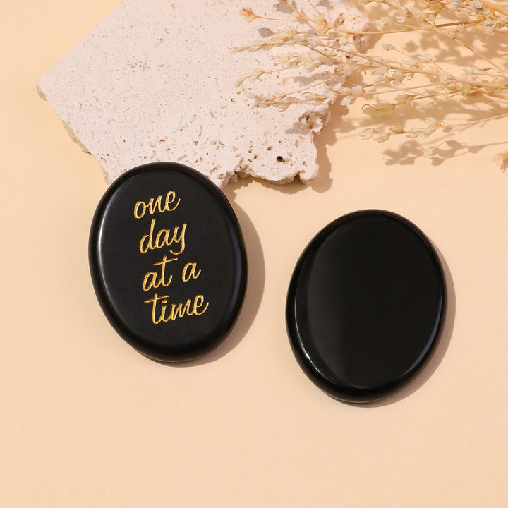 Black round pocket crystal stone with gold “one day at a time” text