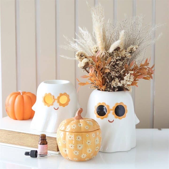 White ghost oil burner and wax warmer with orange glasses on a base.