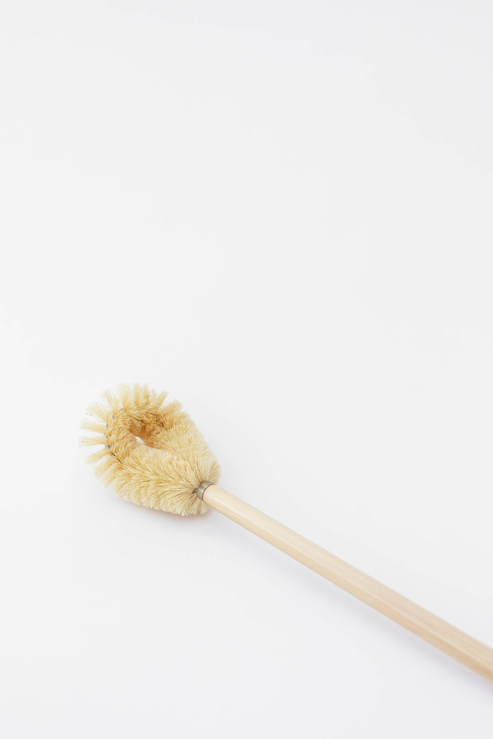 Angle view of beige bristle toilet brush head on light wood handle