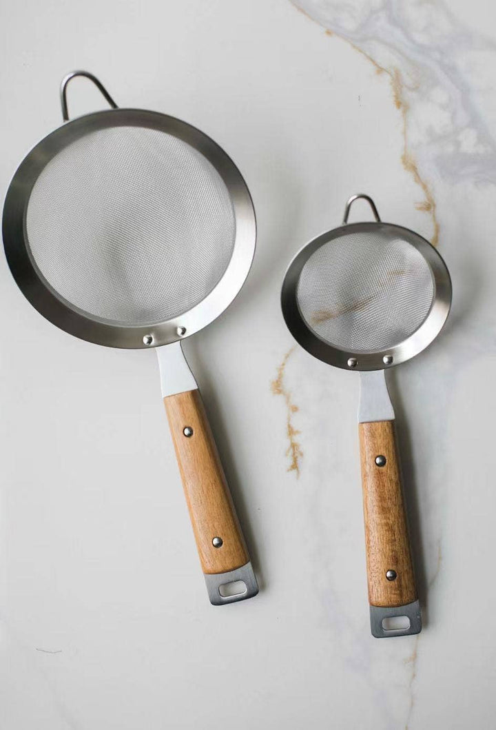 Round mesh strainer with dark metal rim and wood handle, hanging loop at top