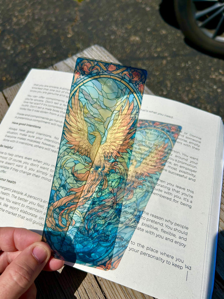 Phoenix-themed bookmark with blue and teal artwork inserted in an open book