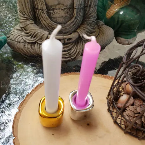 Ceramic candle holders with gold and silver bases, holding white and pink candles