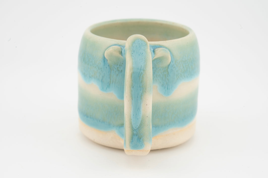 Ceramic mug with turquoise-blue glaze and front handle detail.