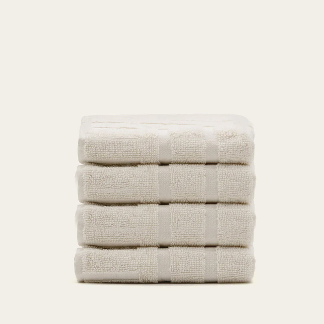 Folded cotton towels in light ecru with subtle raised stripe texture.