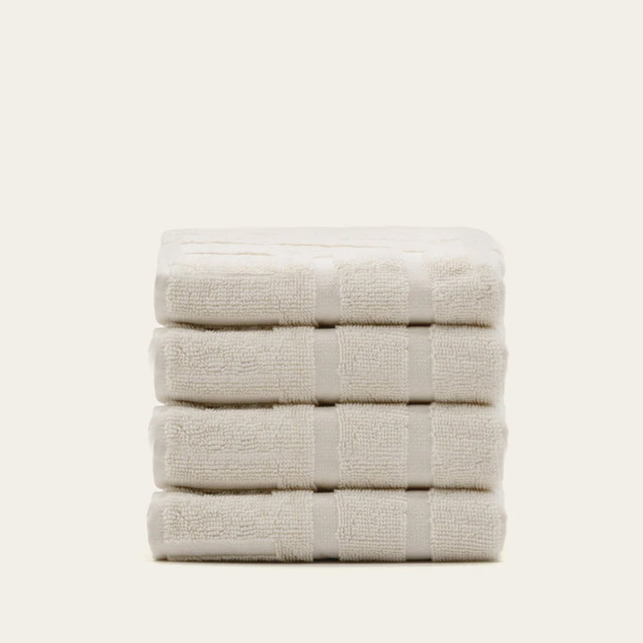 Folded cotton towels in light ecru with subtle raised stripe texture.