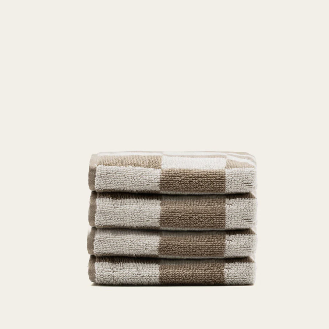 Folded cotton towels with ecru and tan check bands.