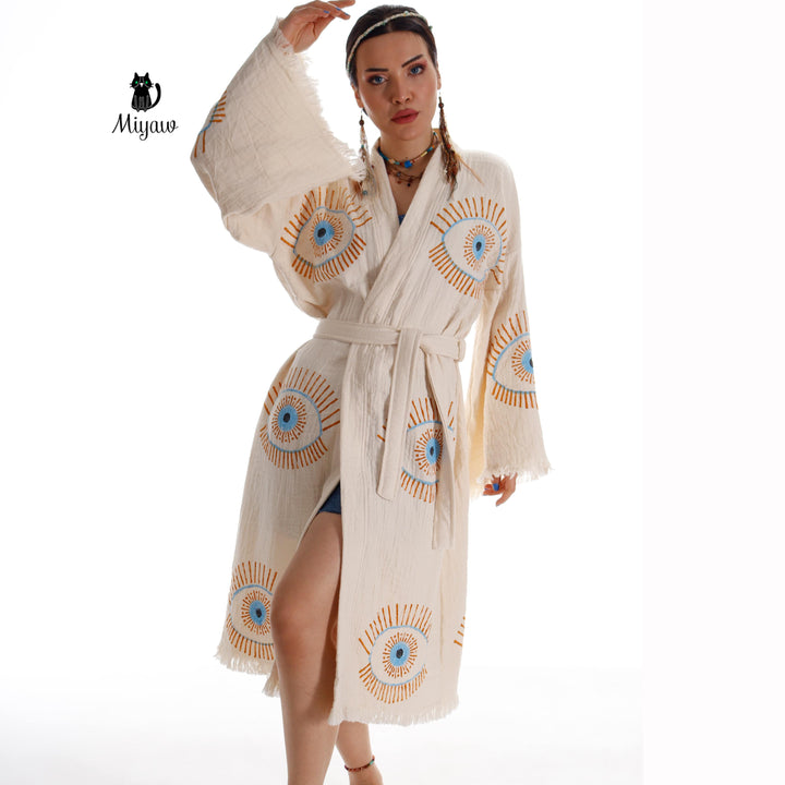 Beige cotton caftan with blue evil-eye prints, tie waist belt, fringe sleeves