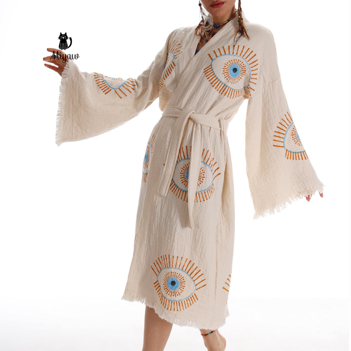 Beige cotton caftan with large blue evil-eye medallion, open flared sleeves, tie waist