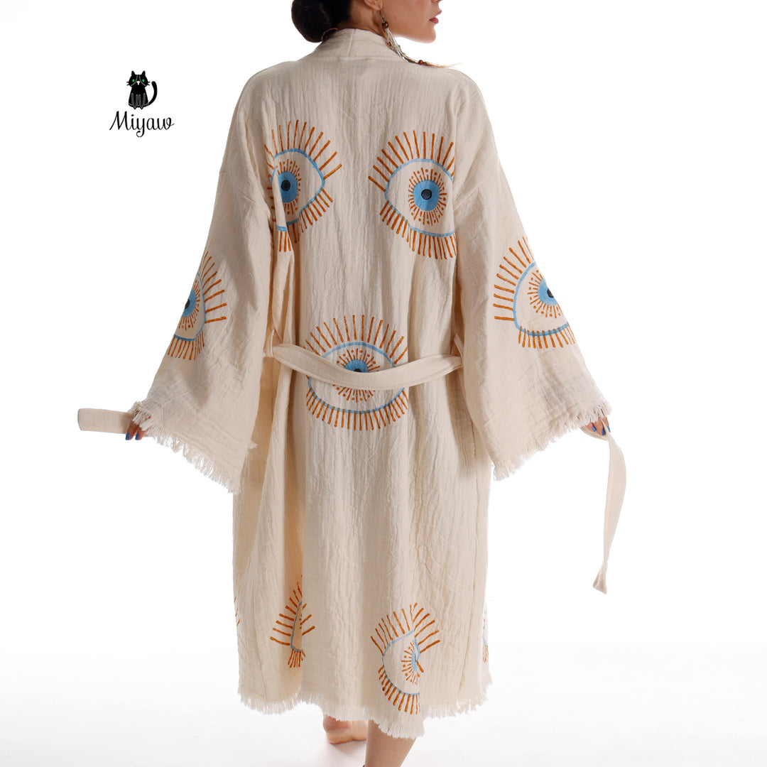 Beige cotton caftan back view with evil-eye prints, tie belt, flared fringe sleeves