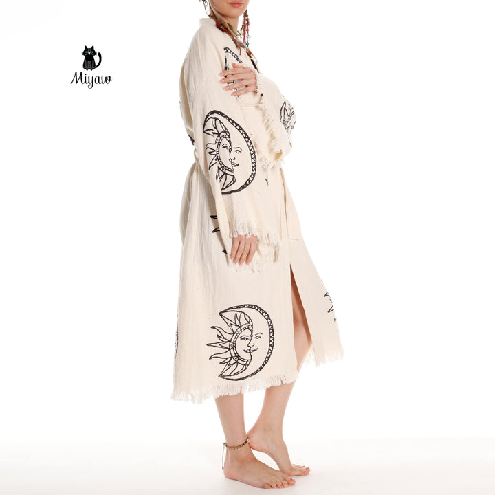 Beige organic cotton kimono robe with moon-and-sun face print, open front, fringe trim