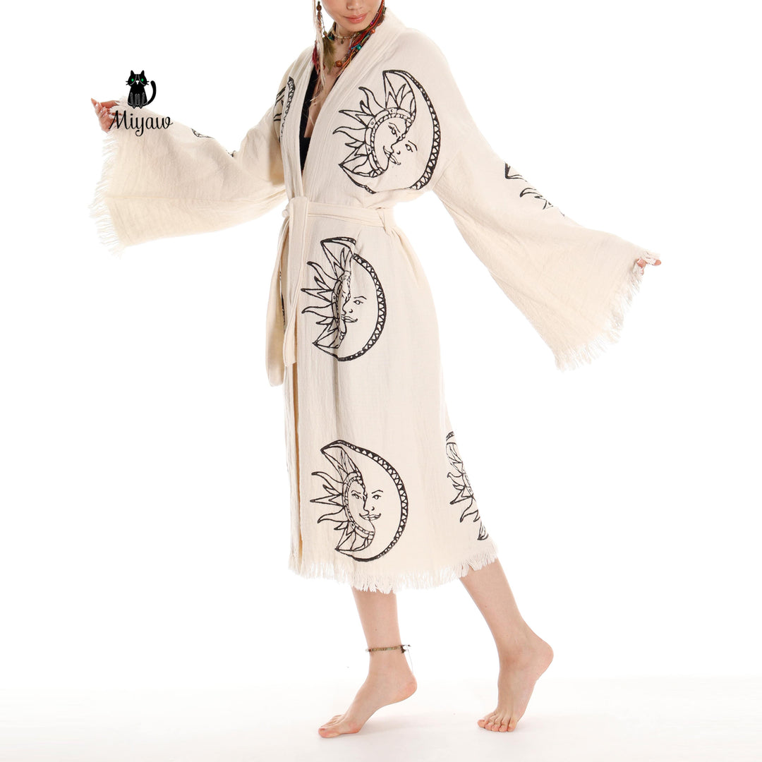 Beige organic cotton kimono robe with moon-and-sun face print, belted waist, tassel fringe