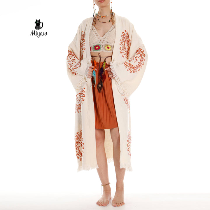 Beige cotton kimono robe worn open, orange sun-face prints and tasseled cuffs