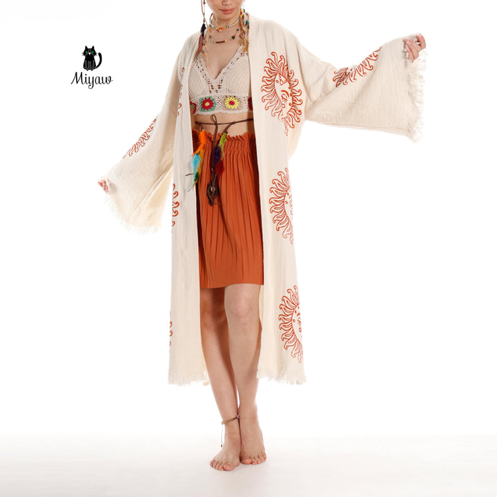 Beige cotton kimono robe with orange sun-face print; model holds sleeve edge
