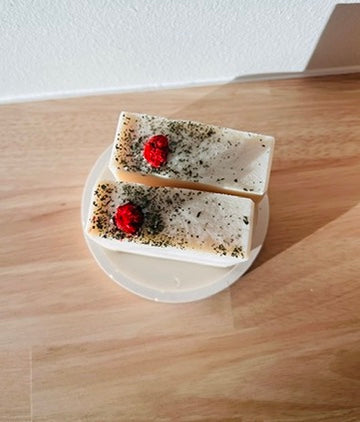 Handmade soap bars with red blossoms and dark speckles, in white tray