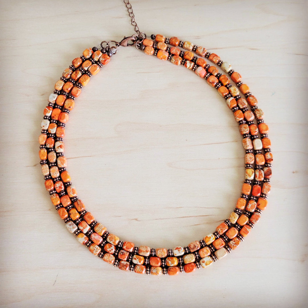 Triple strand beaded necklace with orange and cream beads and bronze chain clasp