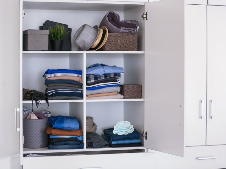 Open closet cabinet with neatly stacked fabric and a light blue wax flower sachet