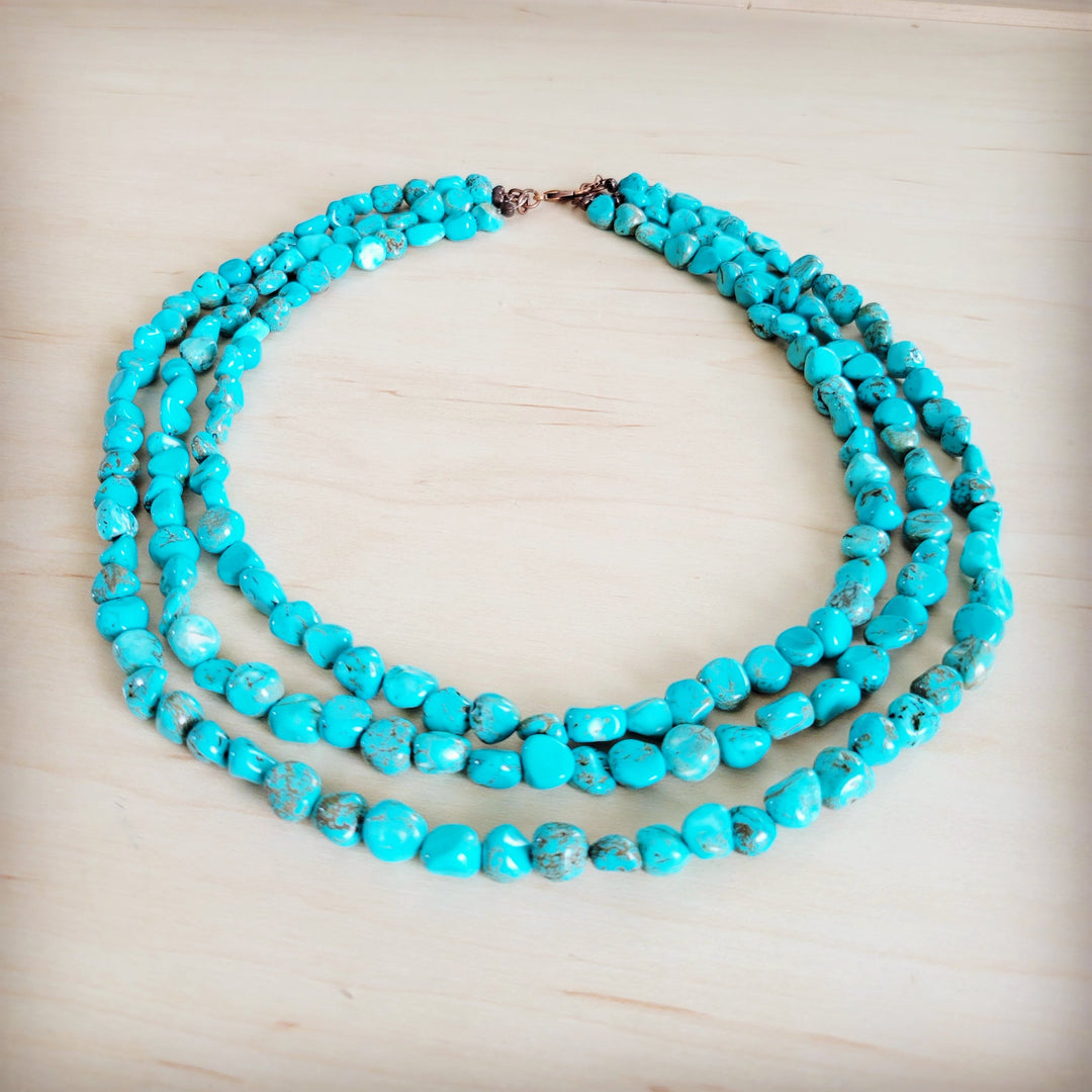 Triple-strand turquoise bead necklace with layered rows and central metal connector
